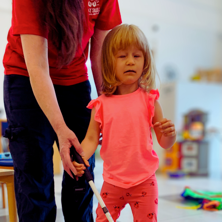 Young child with a visual impairment holding a white stick